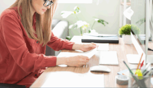 A woman in front of a computer with a piece of paper.